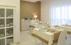 Ein Hotel-Speisesaal mit einemBuffet, einem Esstisch mit Stühlen und einem Schrank mit Geschirr.