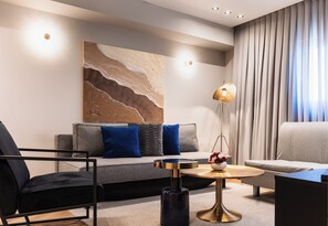 Una sala de estar moderna con un sofá, sillones, una mesa de centro y un cuadro en la pared.