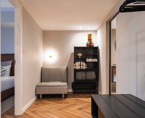 A modern room with a sofa, a wooden floor, a bookshelf with decorative items, and a bed with pillows. - Sphera Eilat Hotel (Eilat)
