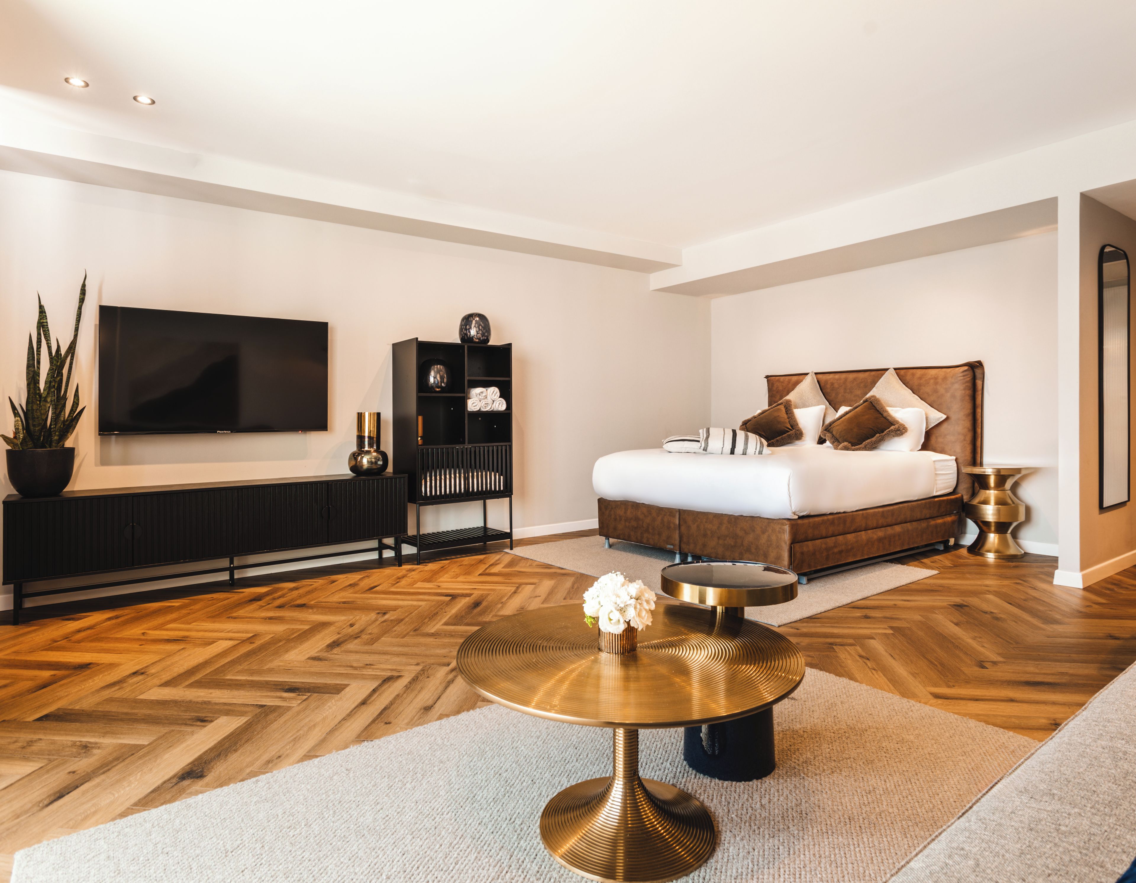 A modern bedroom with a large bed, a TV, a console table, and a round coffee table.