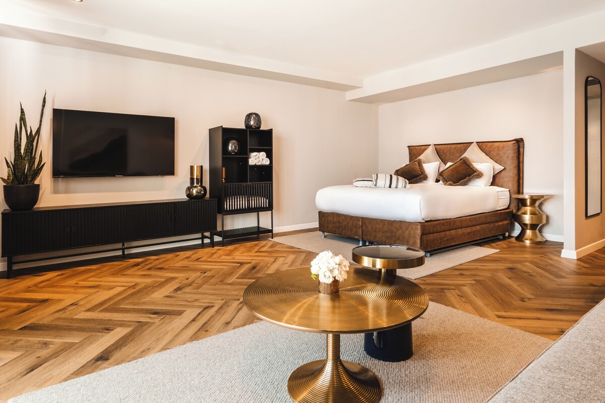 A modern bedroom with a large bed, a TV, a console table, and a round coffee table.