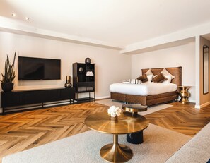 A modern bedroom with a large bed, a TV, a console table, and a round coffee table. - Sphera Eilat Hotel (Eilat)
