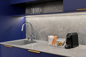 Una cocina moderna con un lavamanos doble, una cafetera y un recipiente con utensilios.