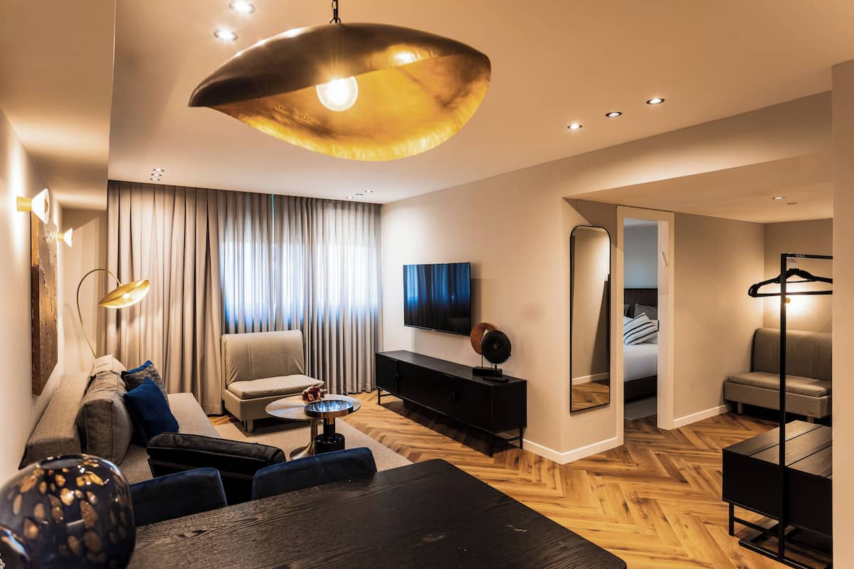 A modern living room with a sofa, armchairs, a dining table, and a TV.