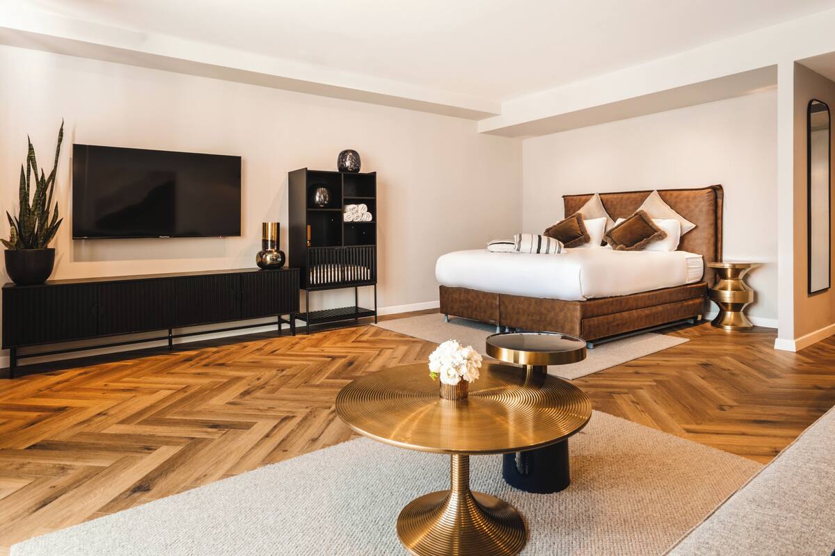A modern bedroom with a large bed, a TV, a console table, and a round coffee table.