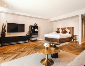 A modern bedroom with a large bed, a TV, a console table, and a round coffee table.