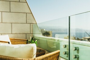 A balcony with wicker furniture, a cushion, and a potted plant. - Sphera Eilat Hotel (Eilat)