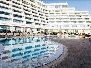 A modern hotel with a large pool, multiple balconies, and a clear sky. - Sphera Eilat Hotel (Eilat)