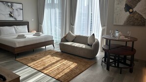 A modern hotel room with a bed, sofa, dining table, and artwork. - Dubai Marina Walk Gem (Dubai)