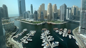 A marina with numerous boats docked, surrounded by high-rise buildings and a clear sky. - Dubai Marina Walk Gem (Dubai)