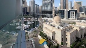 A high-rise building with a view of a marina and a mosque with a dome. - Dubai Marina Walk Gem (Dubai)