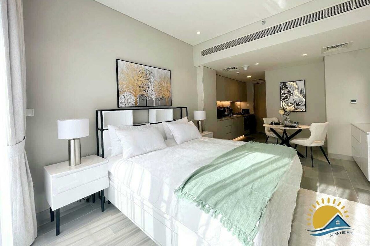 A modern hotel room with a large bed, bedside tables, a desk, and a chair.