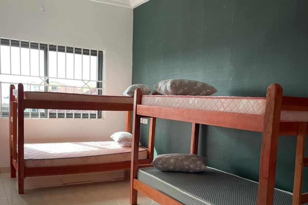 A room with two bunk beds, a window with bars, and a green wall.