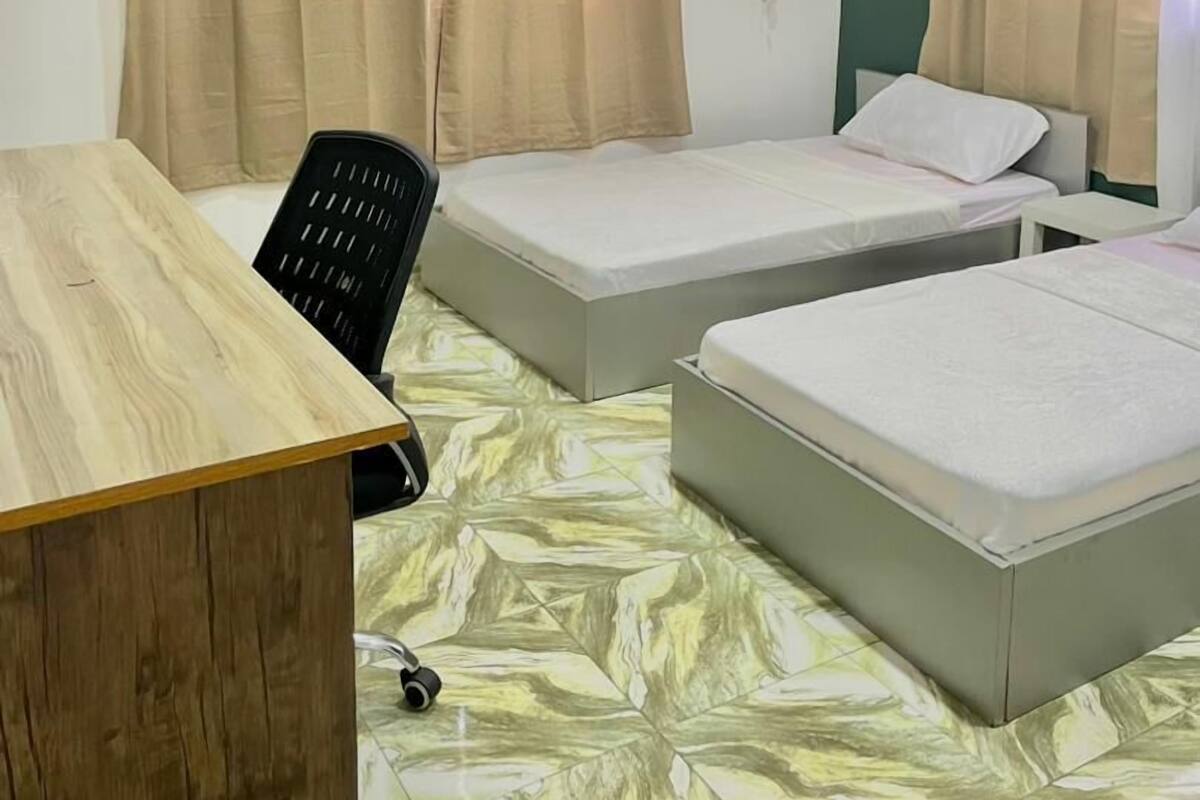 Una habitación con dos camas, un escritorio, una silla y un ventilador de techo.