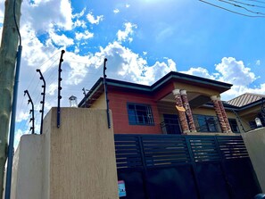 A residential building with a gated entrance, a balcony, and a clear sky. - Serene Hostel Accra (Adenta Municipality)