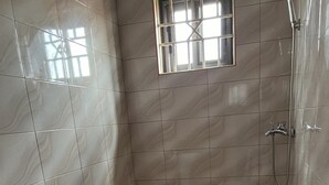 Uma casa de banho com lavatório, sanita, chuveiro e uma janela com grades.