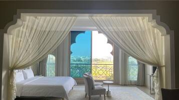 A bedroom with a bed, a chair, a small table, and a view of a balcony.