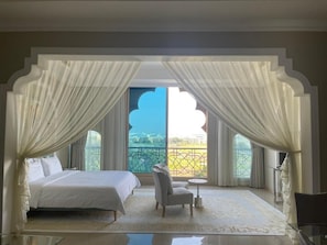 Un dormitorio con una cama, una silla, una mesita y vistas a un balcón.