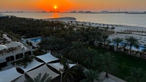 Un complexe hôtelier doté d’une piscine, de palmiers et offrant une vue sur le coucher de soleil.