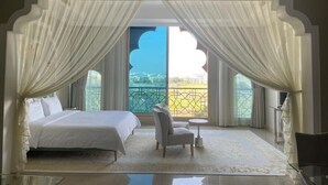 Une chambre à coucher avec un lit, une chaise, une petite table et une vue sur un balcon.
