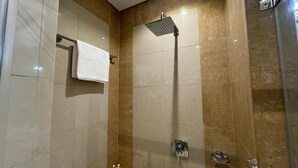 Une salle de bain avec une douche, un porte-serviettes et un lavabo.