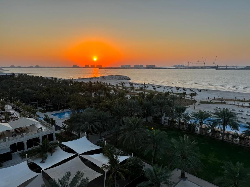 A resort with a swimming pool, palm trees, and a sunset view.
