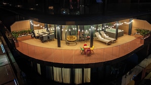 A circular outdoor lounge area with seating, a hot tub, and string lights. - Rainbow Residence (Batumi)