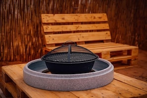 A round stone grill on a wooden table with a wooden bench in the background.