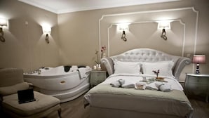 Habitación de hotel con una cama grande, una zona de estar separada con una silla, una bañera y un escritorio con lámpara.