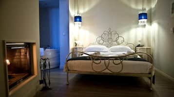 A bedroom with a metal bed frame, bedside lamps, a nightstand, and a fireplace.