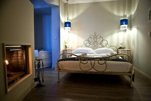 A bedroom with a metal bed frame, bedside lamps, a nightstand, and a fireplace.