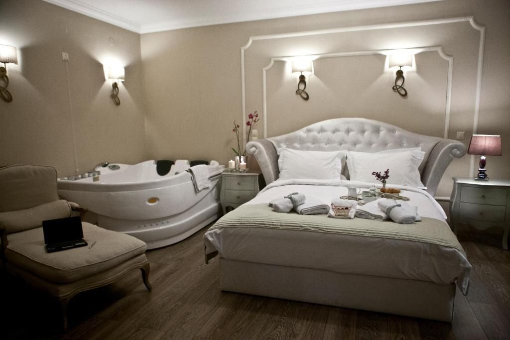 A hotel room with a large bed, a separate sitting area with a chair, a bathtub, and a desk with a lamp.