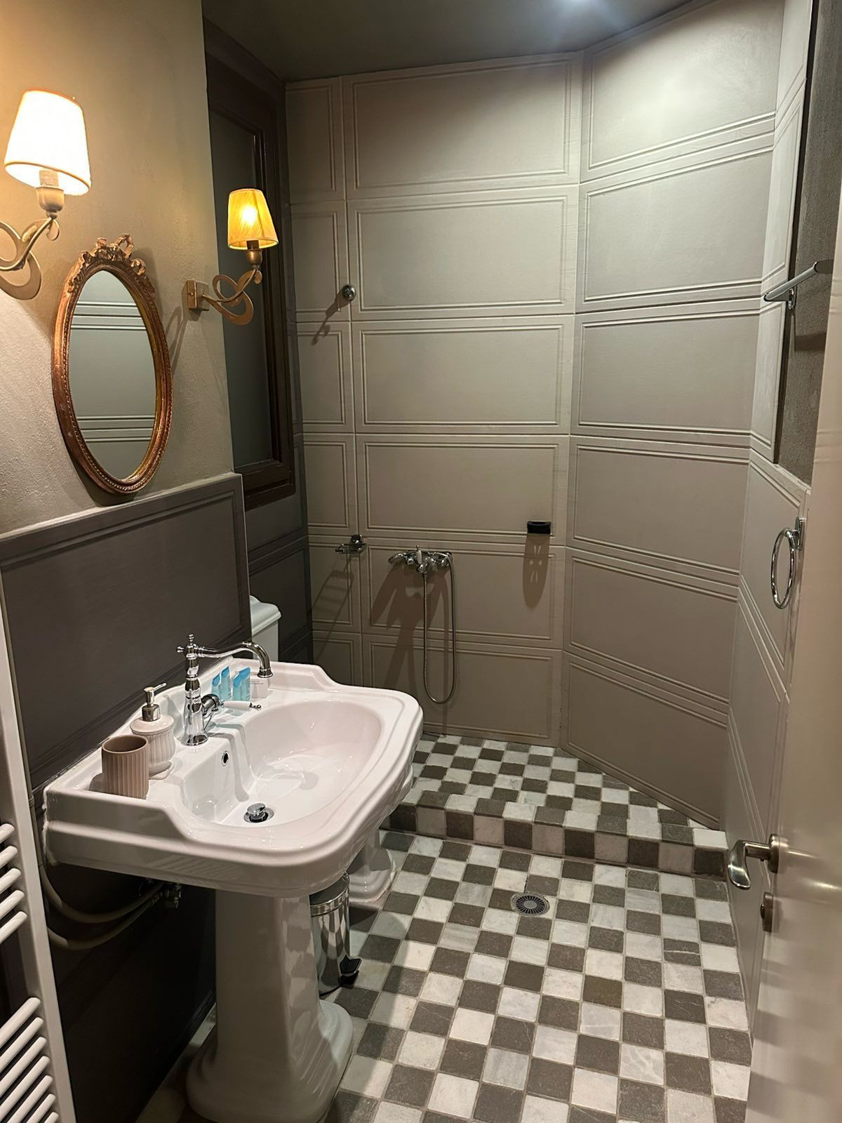 A bathroom with a checkered floor, a sink with a mirror, and a shower area.