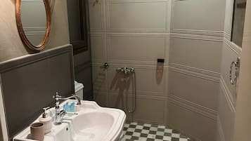 A bathroom with a checkered floor, a sink with a mirror, and a shower area.