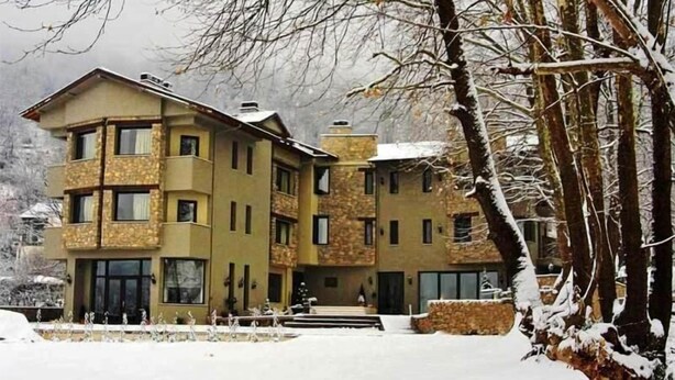 Un edificio de varios pisos con fachada de piedra y numerosas ventanas.