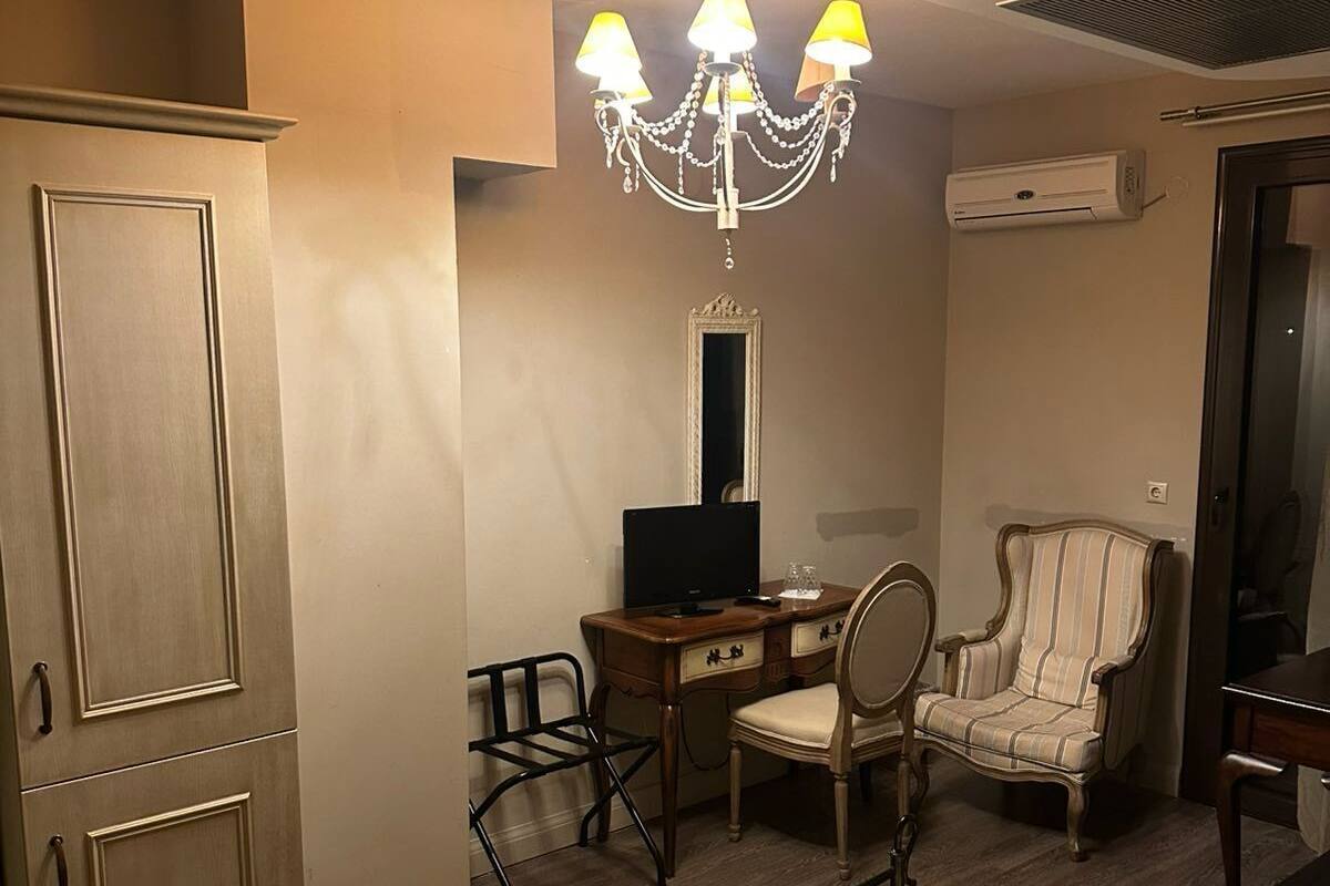 Una habitación de hotel con cama, escritorio con computadora, silla, armario y candelabro.