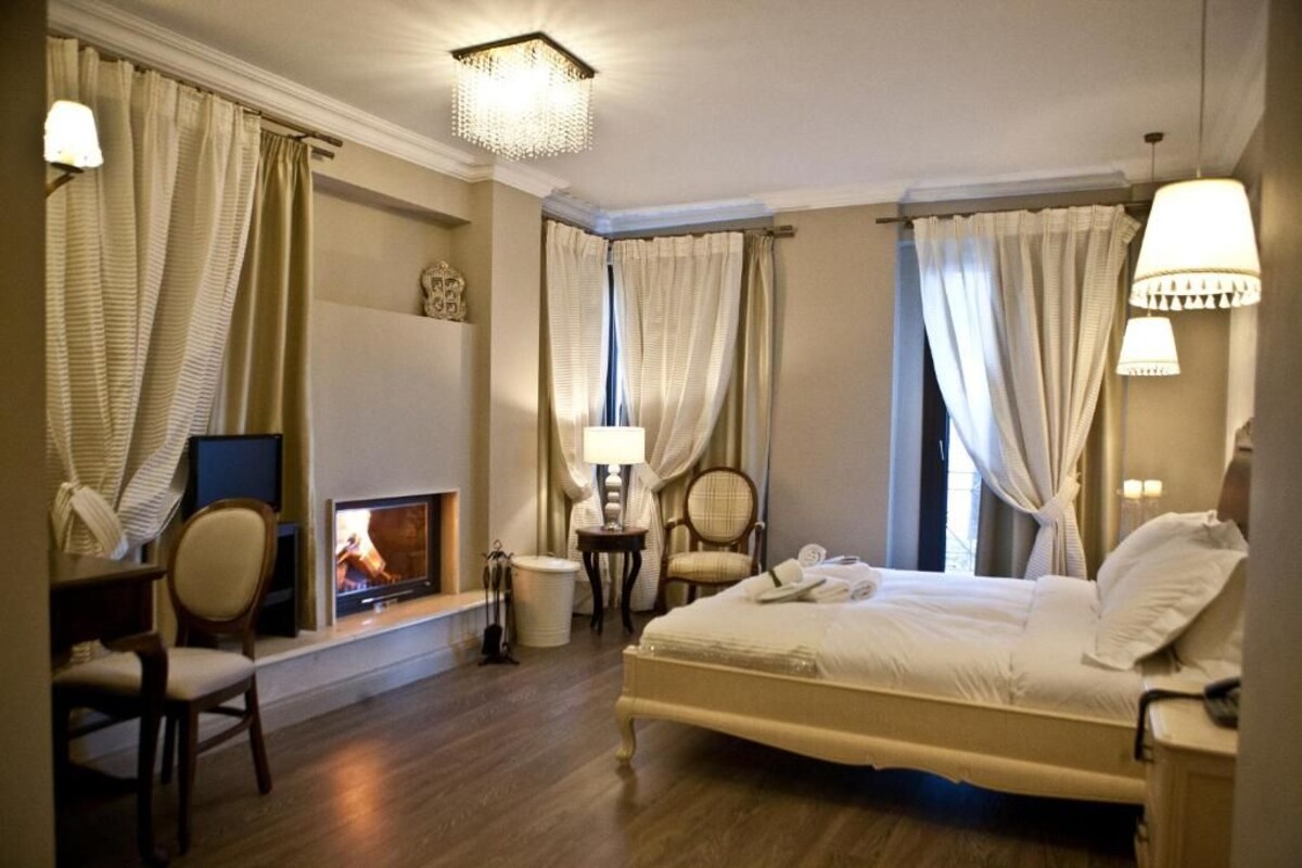 A hotel room with a bed, a television, a fireplace, and a desk with a chair.