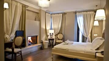 A hotel room with a bed, a television, a fireplace, and a desk with a chair.