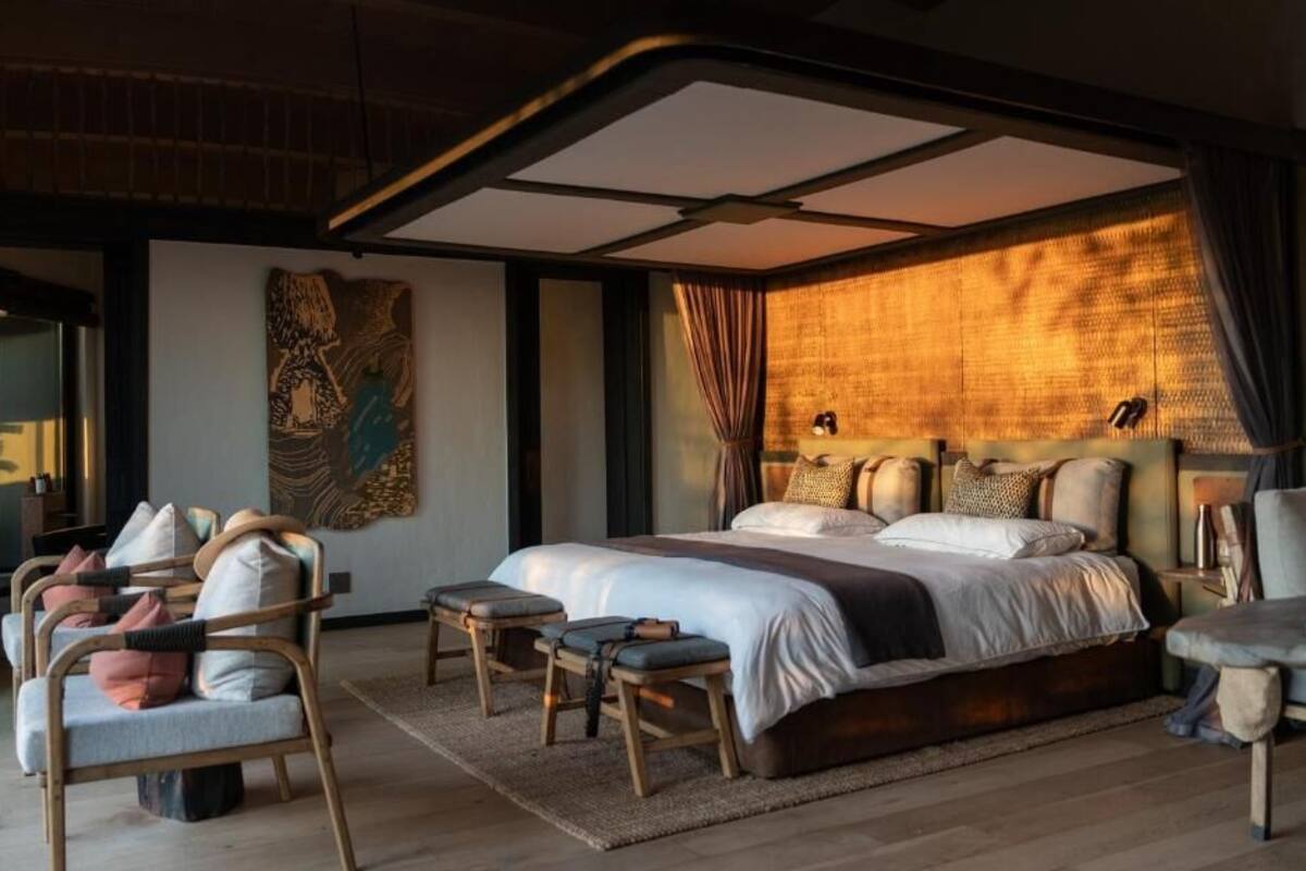 A modern bedroom with a large bed, wooden furniture, and a unique ceiling design.