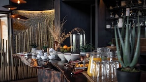 Uma área de bar com bancada de madeira, diversos copos e um vaso decorativo.