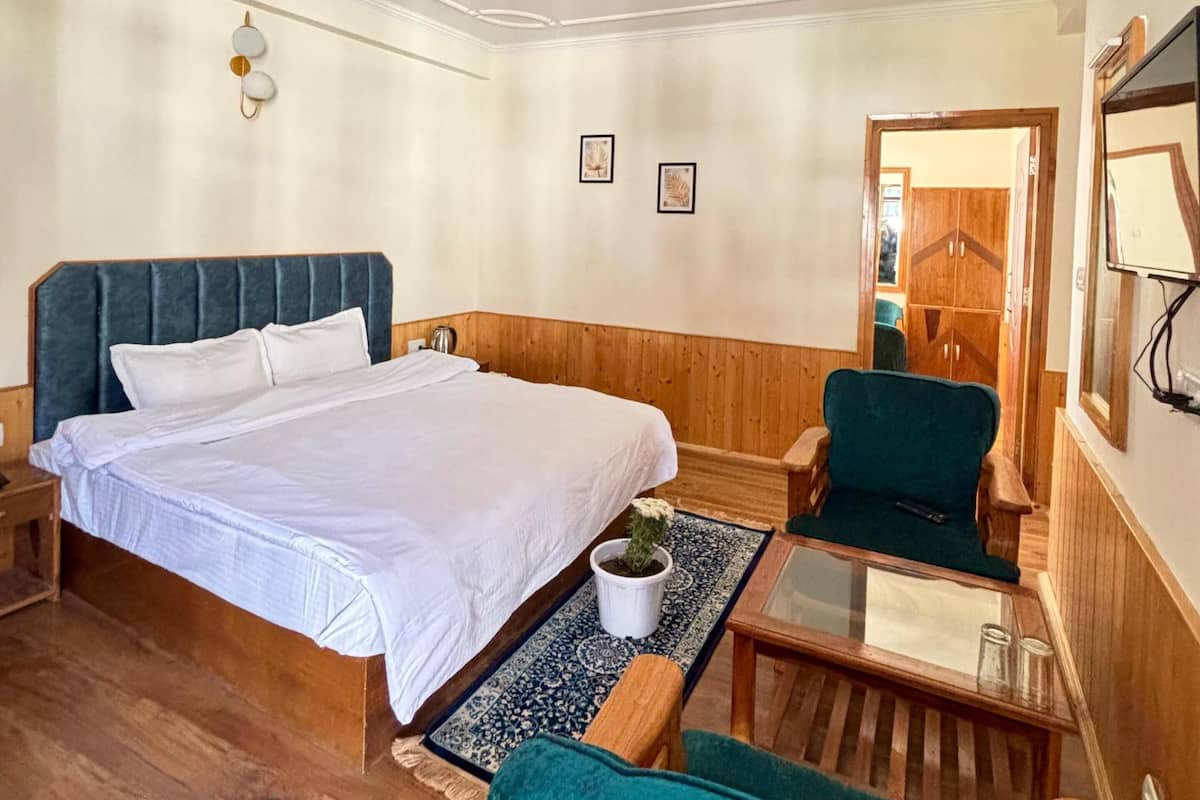 Una habitación de hotel con una cama, un escritorio, una silla, una planta en maceta y un espejo.