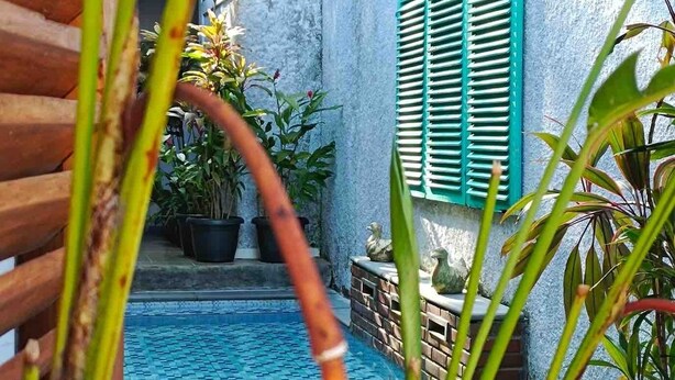 A pool area with a blue tiled floor, green shutters, and potted plants. - Serene 2-bedroom villa with AC in welcoming Jogja (Jogja)