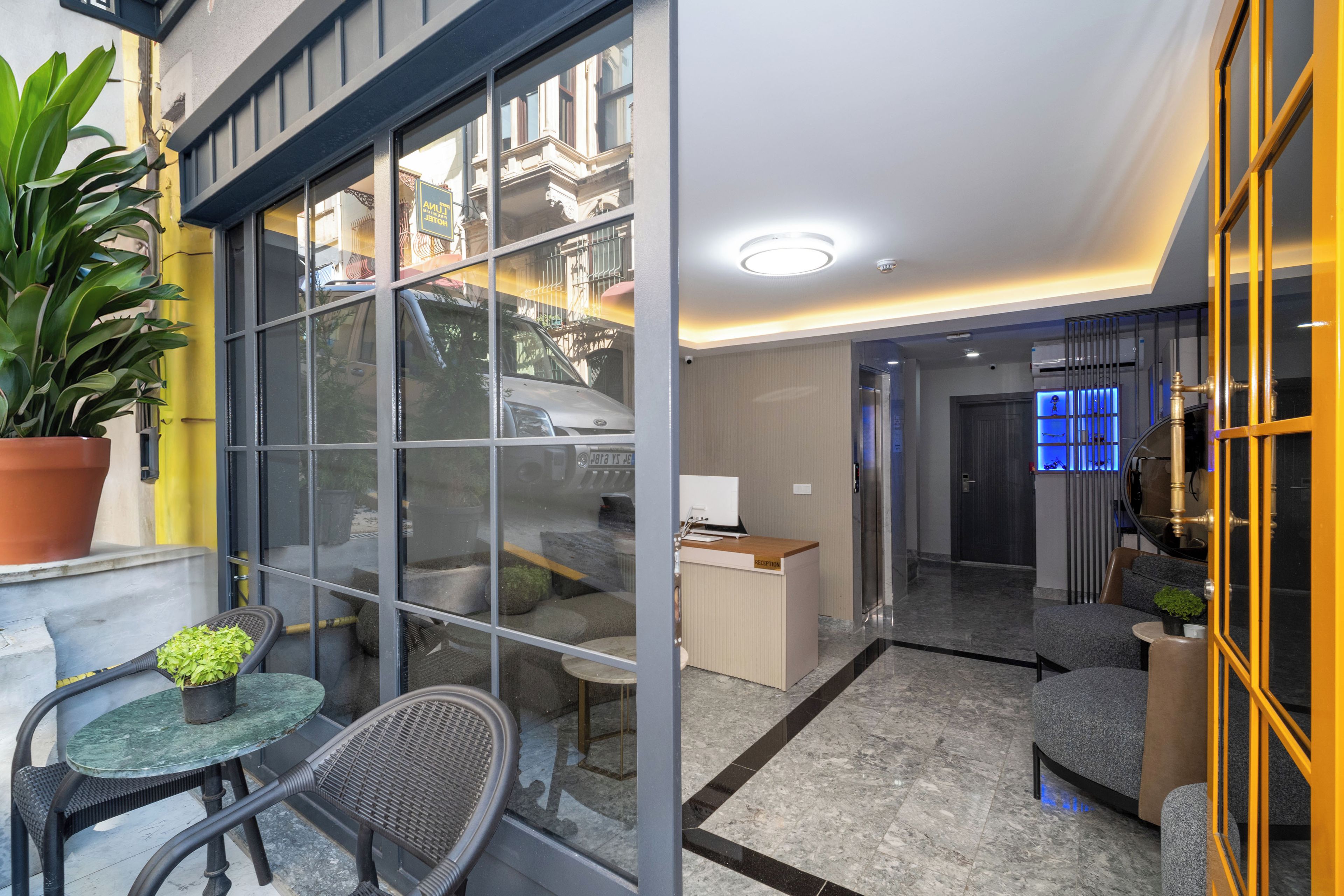 A modern hotel lobby with a glass partition, a reception desk, and seating areas.