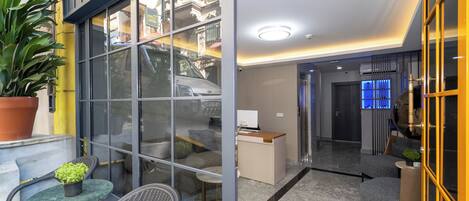 A modern hotel lobby with a glass partition, a reception desk, and seating areas.