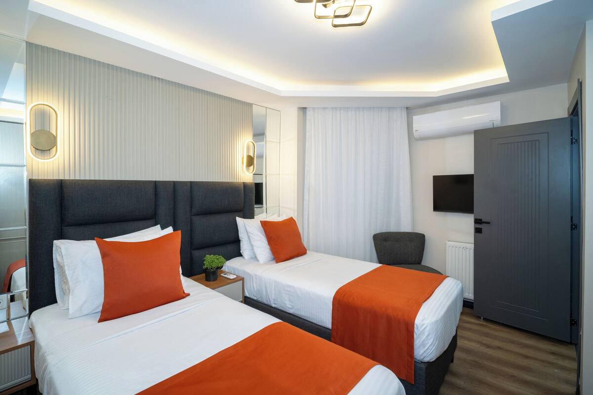 A hotel room with two beds, a seating area, a television, and a door.