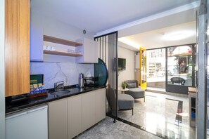 A modern kitchen with a marble countertop, wooden cabinets, and a black-framed glass door leading to a seating area. - Robin Hotel Istanbul (Istanbul)