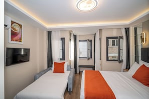 Ein Hotelzimmer mit zwei Betten, einem Fernseher, einem Spiegel und einem Fenster mit Vorhängen.