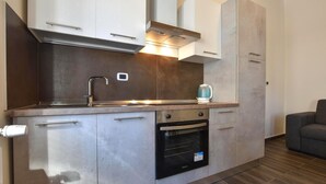 Een kleine keuken met een inbouwoven, een spoelbak en een waterkoker.
