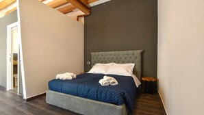 Een slaapkamer met een bed, nachtkastje en een houten kruk.