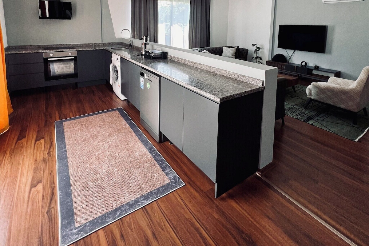 Moderni keittiö, jossa on integroidut kodinkoneet, ruokailutila ja oleskelualue.